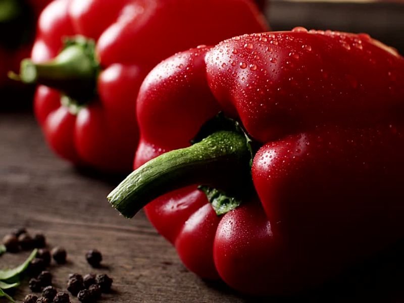 prikaz dve crvene paprike na drvenom stolu
