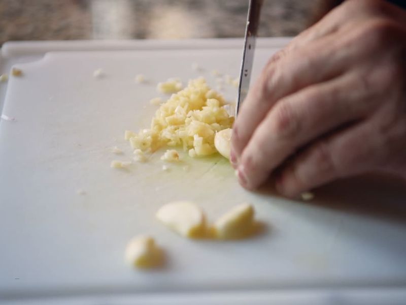 osoab seče beli luk na dasci