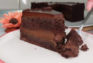 Parče bogate čokoladne torte sa kremastim filom i glatkom čokoladnom glazurom