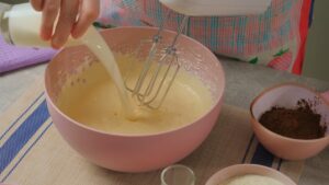 Dodavanje mleka u umućenu smesu za čokoladni biskvit tokom pripreme ledenih kocki