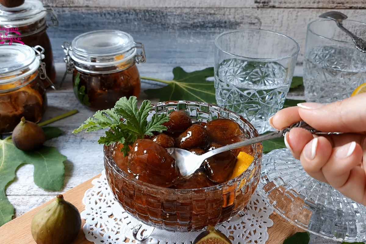 Domaće slatko od smokava u staklenoj činiji sa kašikom i teglama u pozadini.